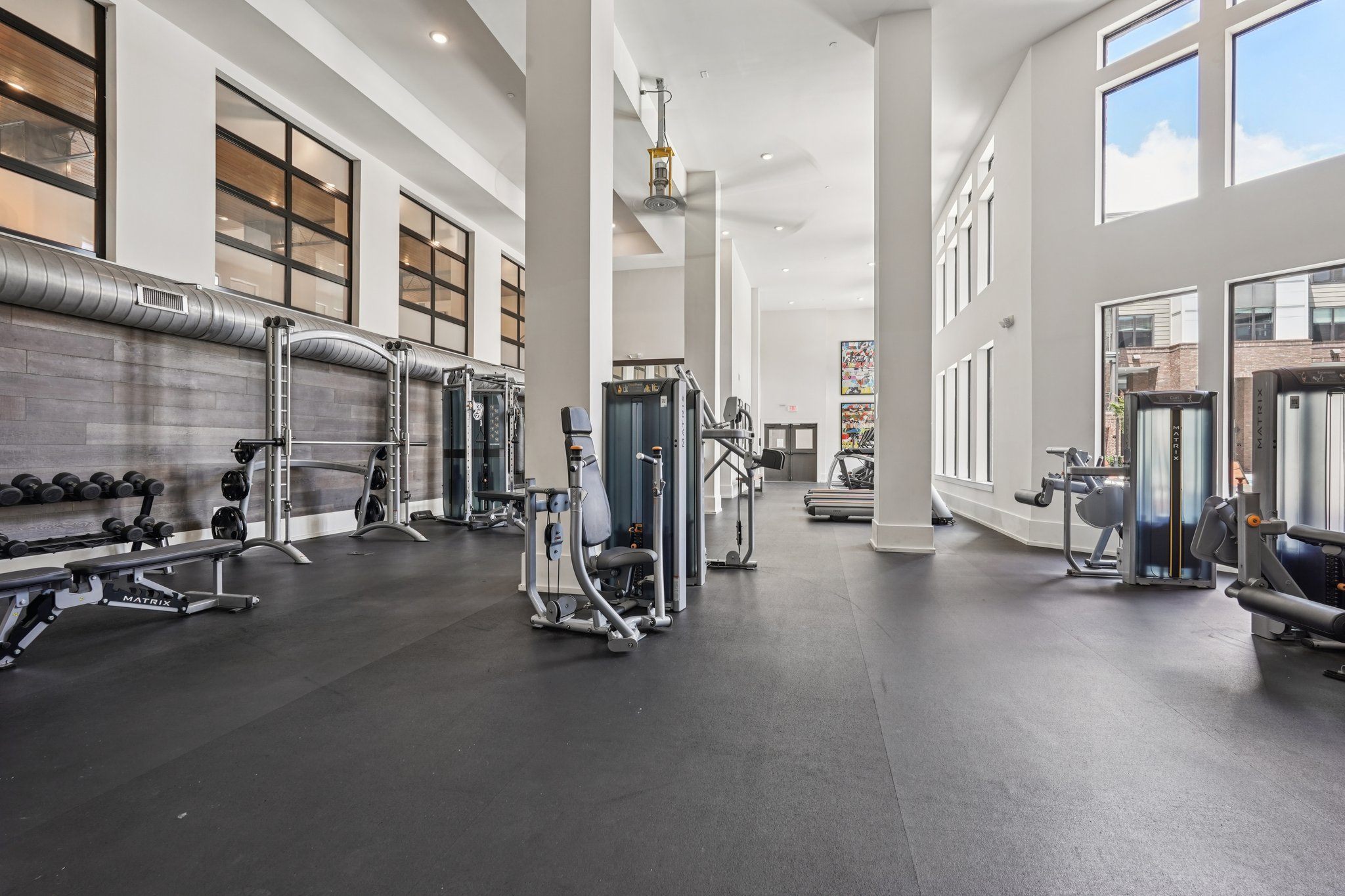 A spacious gym with a variety of equipment and a large mirrors on the wall.